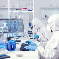 Chemist in ppe suit typing on keyborad Chemist in ppe suit typing on keyboard checking virus development in equipped laboratory. Medical engineer using computer during global pandemic with coronavirus dressed in coverall.